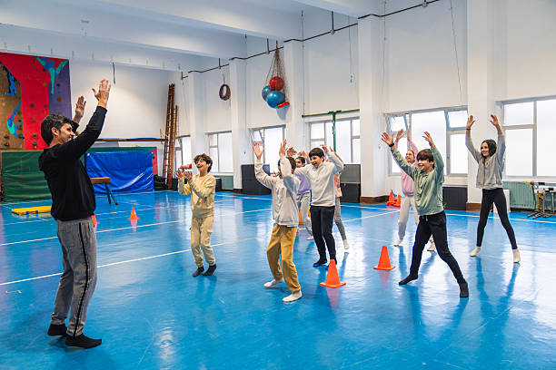 istock Group of elementary age students jumping with their teacher in gym class 2208363497