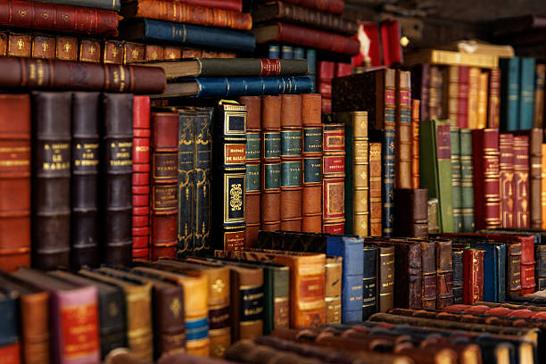 A diverse assortment of books, ranging in size and color, are piled on top of one another