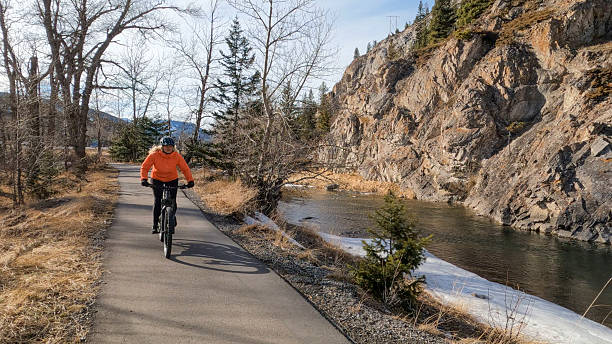 istock Mature woman e-bikes along pathway beside river 2208370588