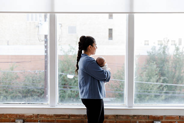 istock Mother Holding Baby, Looking Out Window, Day 2208371160
