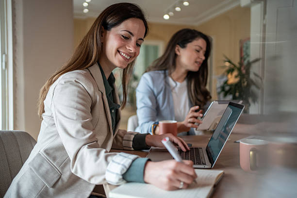 istock Two businesswomen working on laptops and taking notes in modern office 2208373228