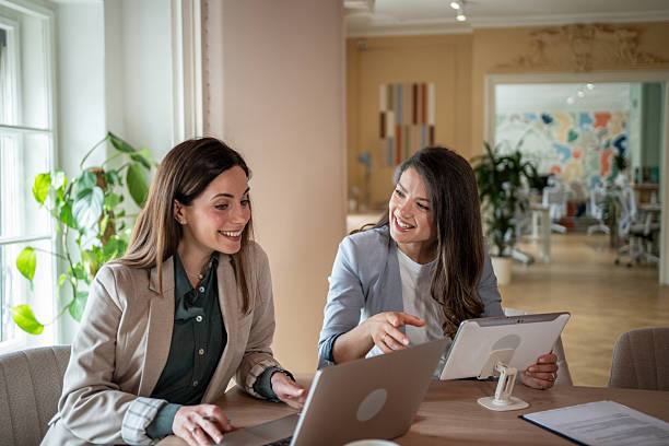 istock Two businesswomen collaborating on project using laptop and tablet in modern office 2208373267