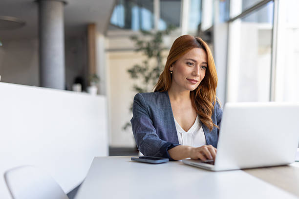 istock Focused young woman typing on laptop in bright office 2208402335