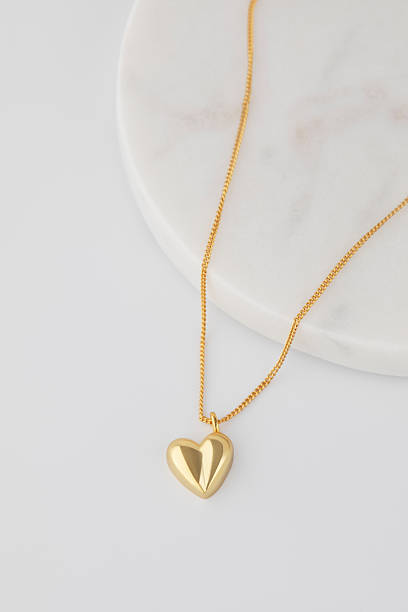 istock Elegant gold heart pendant necklace on marble surface 2208402340