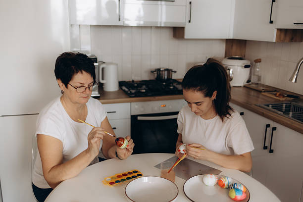 istock Mother and Daughter Painting Easter Eggs in a Bright Kitchen Environment 2208402698