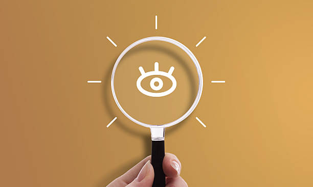 Hand holding magnifying glass with eye icon