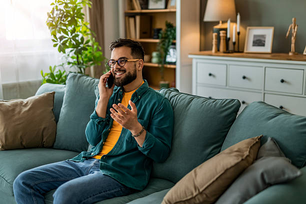 istock Happy young man talking on phone on sofa at home. 2208411692