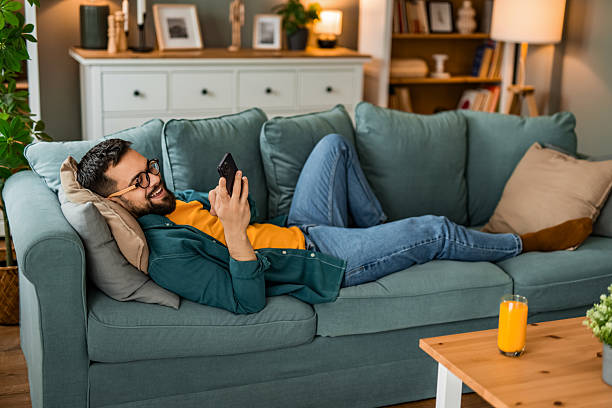 istock Happy young man relaxing on sofa and using smart phone at home. 2208411912
