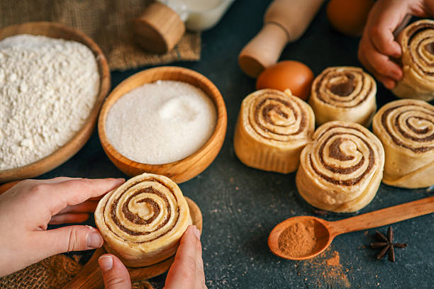 istock Children rolling cinnamon buns on a dark surface with flour, sugar, eggs, and milk, capturing a cozy baking scene, perfect for family cooking themes 2208416355