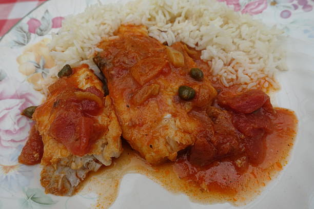 istock Cod fillet cooked in tomato sauce with capers and condiments served with basmati rice 2208416940