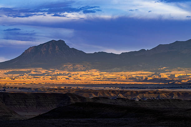 Henry Mountains with Canyons Sunset View - Red rock canyons and cool sky with dark mountains rising up from valley floor in desert landscape environment.