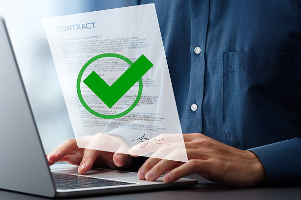 istock Signing electronic contract agreement with digital signature. Check mark icon. Technologies of contract authentication and certification system. Businessman using laptop computer at desk in office. 2208418133