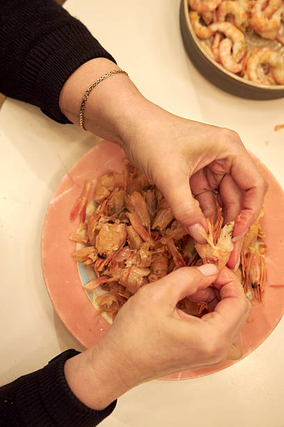 istock a woman peels shrimp at a white table in the kitchen 2208419583
