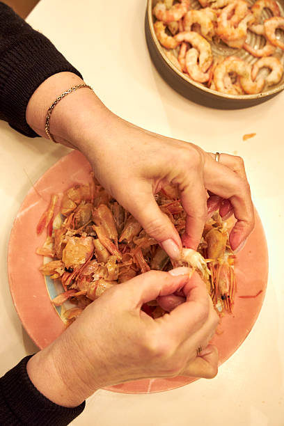istock a woman peels shrimp at a white table in the kitchen 2208419584