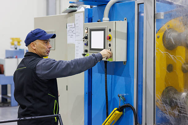 Man working by the machine, electrical insulation tape sheets on the spools, small business manufacturing and warehouse