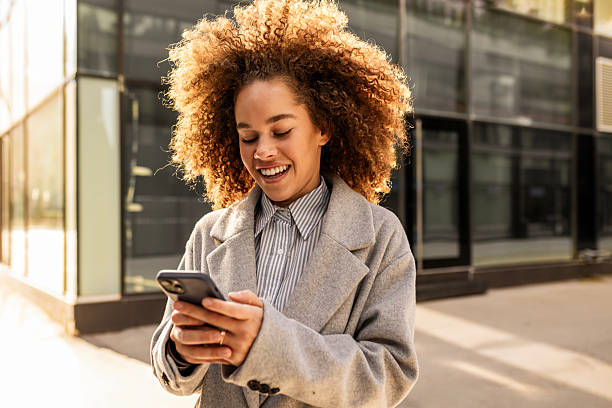 istock Smiling Woman with Curls Engaged in a Phone 2208424279