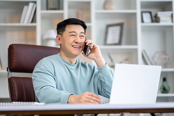 istock Smiling asian man holding smartphone sitting in office. Digital technology applications and solutions for business development. Copy space 2208429028