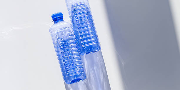 istock Clear plastic water bottles for clean water on white blue background closeup, minimal aesthetic lifestyle banner, top view, flat lay, Naural light, sunlight shadows, caustic light effect, star filter 2208431129