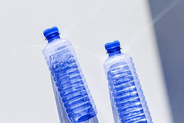 istock Clear plastic water bottles for clean water on white blue background closeup, minimal aesthetic lifestyle photo, top view, flat lay, Naural light, sunlight shadows, caustic light effect, star filter 2208431133