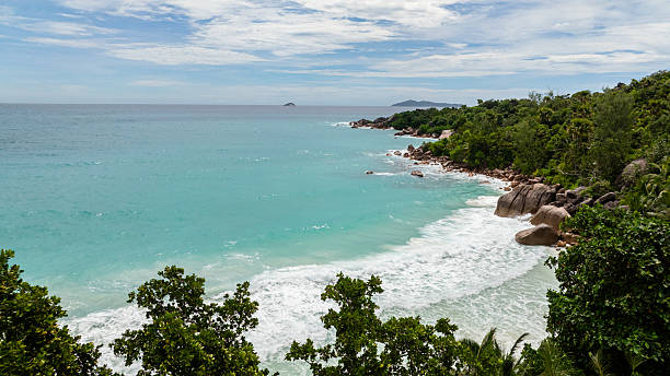 istock Turquoise waters and rocky shoreline surrounded by lush greenery. Praslin, Seychelles. 2208431212