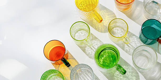 istock Colorful glowing glass cups on white, casting artistic light reflections and shadows in natural sunlight. Summer drink concept, minimal trend banner, pattern of transparent glasses, caustic effects 2208431666