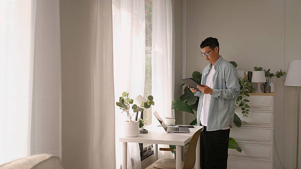 istock Relax Asian man working on digital tablet drinking coffee. Working at home in the morning. 4K. 2208432659