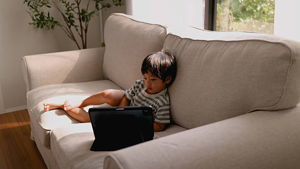 istock Close-up Asian little boy using tablet on sofa watch cartoon , playing game. 2208433082