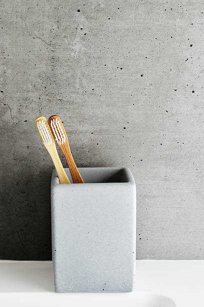 istock Two bamboo toothbrushes with white bristles in square shaped grey concrete toothbrush holder. Natural wooden material, neutral colored photo. Sustainable living concepts, minimal style bathroom 2208433668
