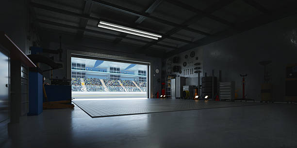 istock 3D Motorsport pit garage overlooking crowded stadium with open roller door 2208434100