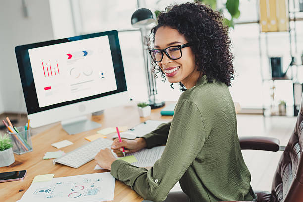 istock Businesswoman working in a modern office with a computer and charts, showcasing professionalism in a well-lit indoor environment 2208436114