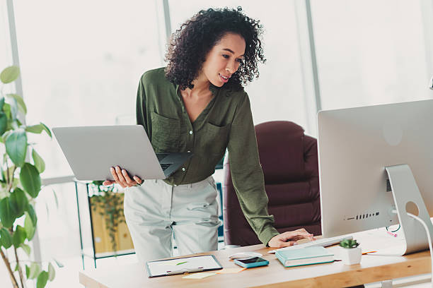 istock Young businesswoman working in a modern office setting, confidently managing tasks with a laptop and desktop monitor 2208436185