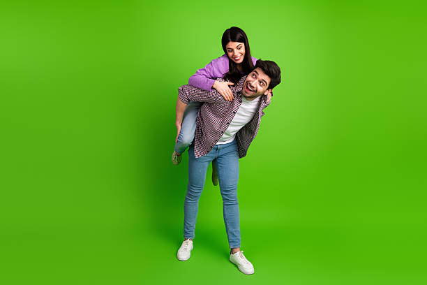 istock Happy young couple having fun in a playful pose on a vibrant green backdrop, showcasing their joy and youthful energy 2208436607
