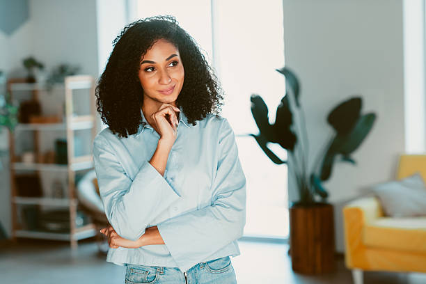 istock Young woman with confident expression posing in a cozy, well lit living space adorned with greenery and bright decor 2208437768