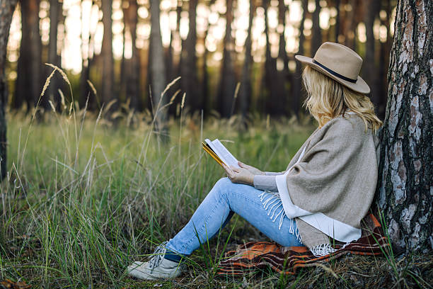 istock Woman reading book outdoors in pine forest 2208438551