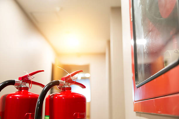 istock Fire extinguisher, Close-up red fire extinguishers tank with fire escape doorway or door exit in the building concepts of protection and prevent for emergency and safety rescue and fire training. 2208438738