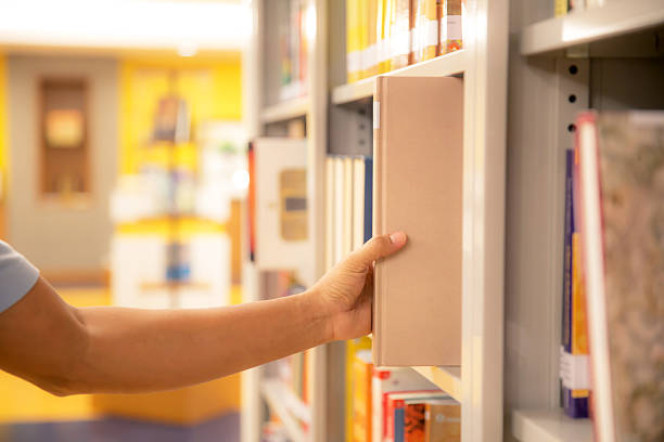 istock Book and library, Close up hand choosing and picking books from bookshelf in library. Concepts of reading textbook and school for student knowledge education or study and learning 2208438759