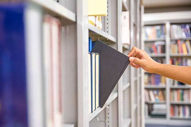 istock Book and library, Close up hand choosing and picking books from bookshelf in library. Concepts of reading textbook and school for student knowledge education or study and learning 2208438773