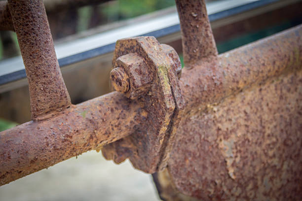 A rusted metal bar with a bolt on it. The bolt is missing. The bar is old and rusty