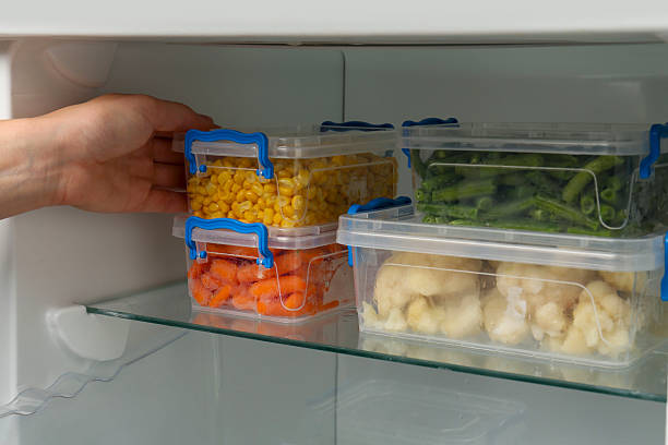istock Woman taking plastic container with frozen corn from refrigerator, closeup 2208440192