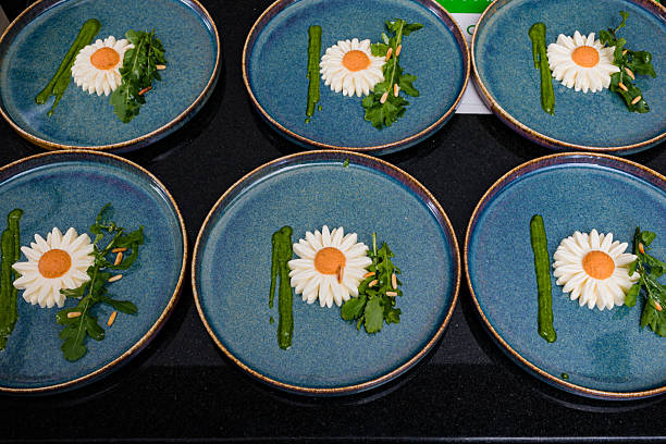 Stock photo showing close-up view of edible flower heads, including dianthus, marigold, daisy, pansy and cornflower petals, in a bowl, ready to be decorative garnishes.