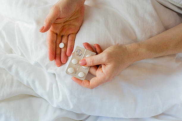 istock Woman taking medication and drinking water in bed 2208442194