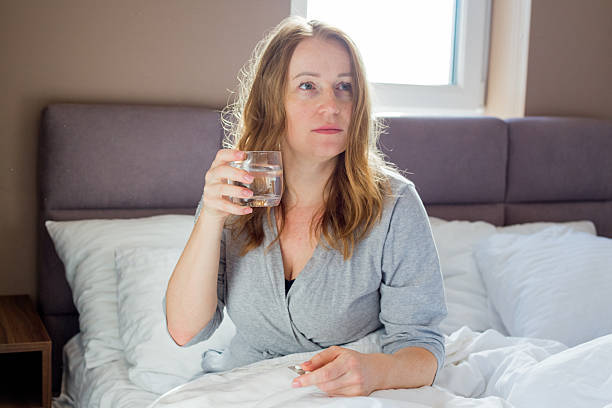 istock Woman taking medication and drinking water in bed 2208442199