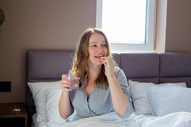 istock Woman taking medication and drinking water in bed 2208442242