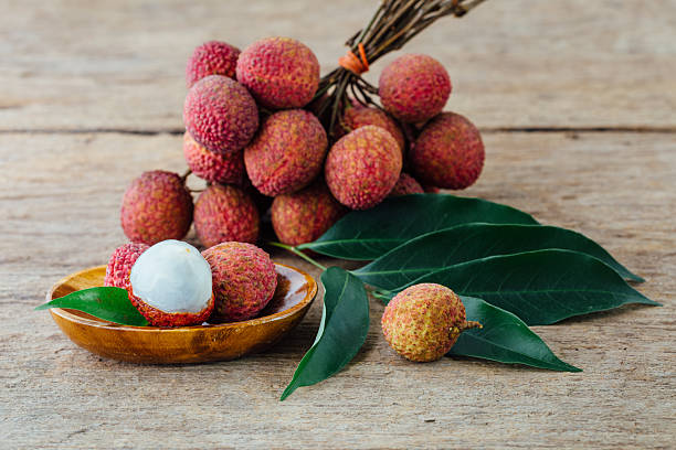 istock Fresh Lychee Fruit with Leaves on Wooden Background in Natural Light Setting 2208443771