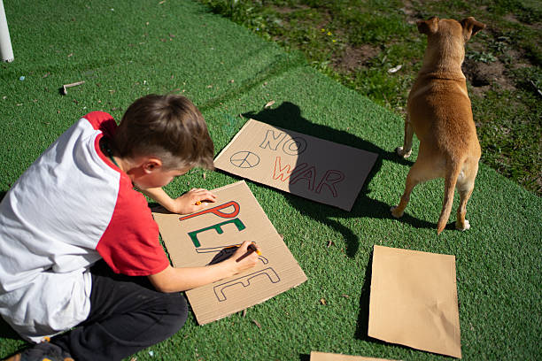 istock Child preparing placards with peace and no war messages in a garden 2208445550