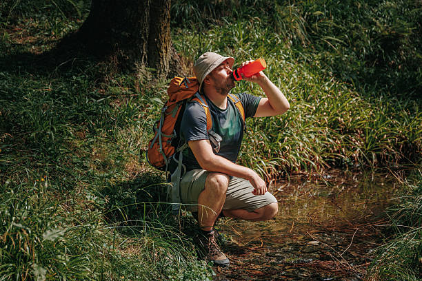 istock Active American guy enjoying a refreshing drink in peaceful woods 2208446659