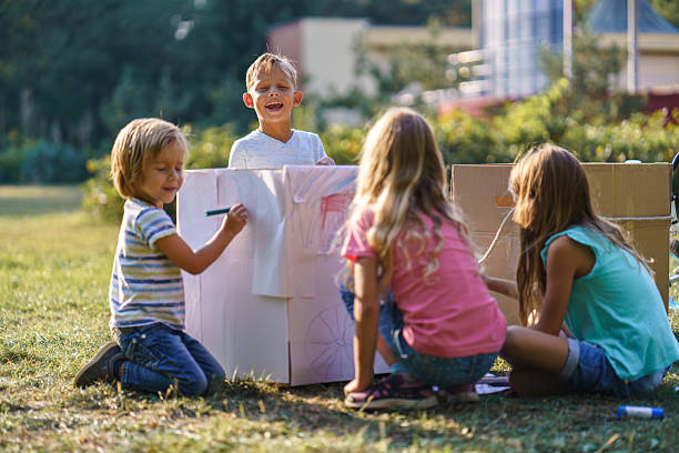 istock Children having fun drawing on carboard box in public park 2208449408