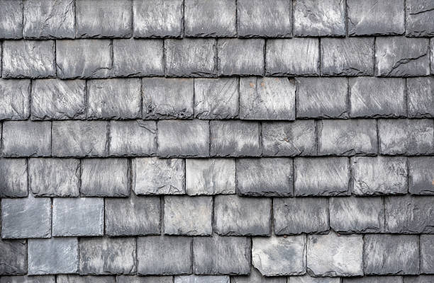 Close up view of gray slate roof tiles creating a seamless pattern, showcasing rustic charm while providing durable protection for the building's exterior design and architecture