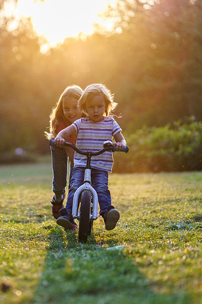 istock Boy riding a bicycle whit help of his sister 2208450136