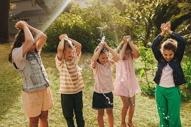 istock Five children enjoying a fun water splash activity on a sunny day outdoors 2208451431